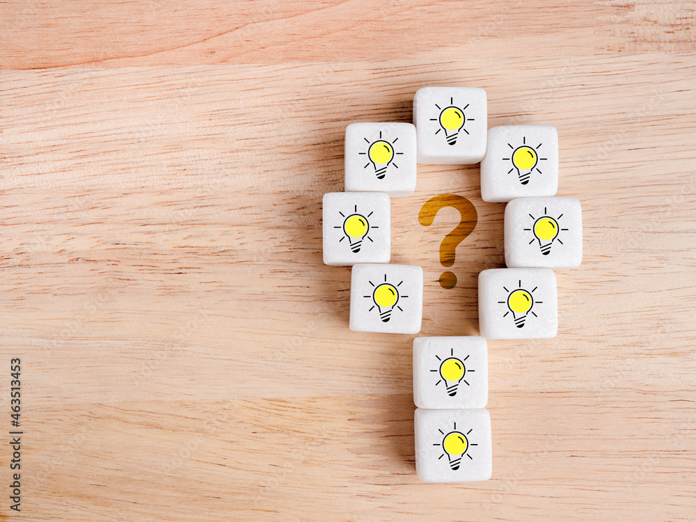 Poster light bulb with yellow light, the icon on white dices around question mark symbol on wood background