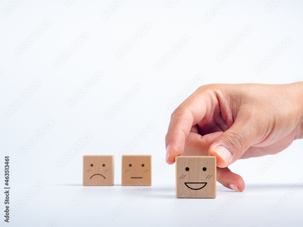 Poster hand choose smile face on wooden cube block on white background with copy space. customer feedback a