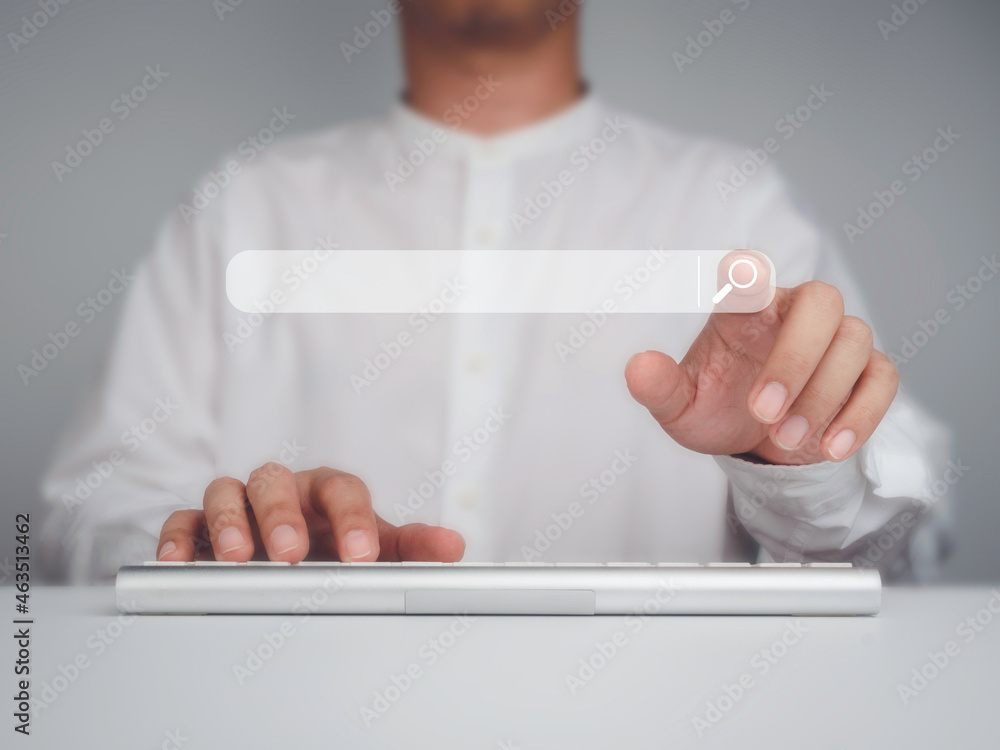 Aufkleber man's hand points to searching icon on search engine bar while using computer keyboard on white desk
