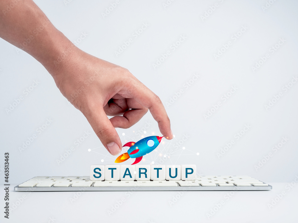 Aufkleber startup concept. hand holding rocket on white dice blocks with the word, startup on keyboard compute