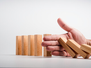 Stopping the domino effect. Business crisis management. Close-up hand interfering collapsing wooden...