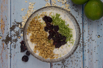 Lemon pai oatmeal with granola and raisins on light blue wooden background