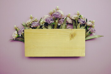 Frame of flowers with wooden banner for tex on purple background