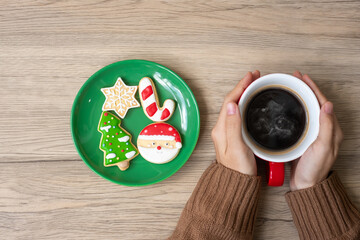 Merry Christmas with woman hand holding coffee cup and homemade cookie on table. Xmas eve, party, holiday and happy New Year concept
