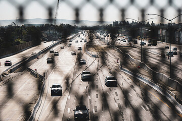 California freeway viewed from behind overpass fence