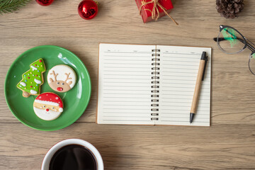 Blank notebook, black coffee cup, Christmas cookies and pen on wood table, Top view and copy space. Xmas, Happy New Year, Goals, Resolution, To do list, Strategy and Plan concept