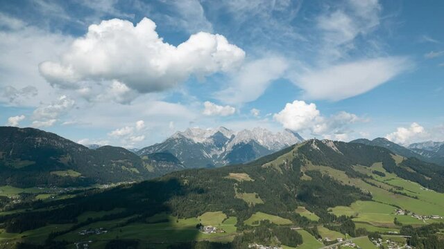 Aerial Drone Hyperlapse Shot of the Brixental with moving clouds in the blue sky and a beautiful view of the alps in the background like the Wilder Kaiser mountain, Austria.