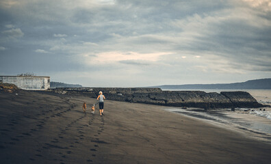 A woman playing with the dogs at the beach.