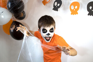 Happy baby with skeleton makeup. Spider web in the hands of a boy on Halloween