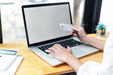 Fototapeta na wymiar Businesswoman shopping online using laptop blank white screen holding credit card. Mock up.