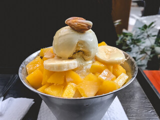 Beautiful and delicious 'Patbingsu' (korean dessert of shaved ice with sweet red beans and fruit) of bananas, mango and almond
