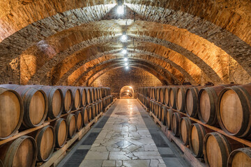 Old wooden barrels with wine in the ancient medieval cellars - 463519695