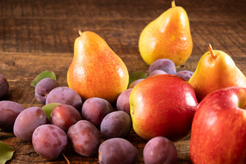 Fresh plums and pears lying on a wooden table.Fresh, juicy fruits lying on a wooden table.
