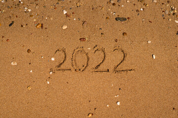 Happy New Year 2022 on the beach. Sand on a beach with a wave by the sea. Winter Vacation on the sea. New Year concept. Top view
