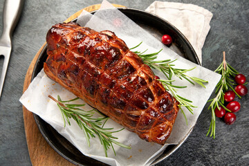 Baked ham with vegetables on dark background.