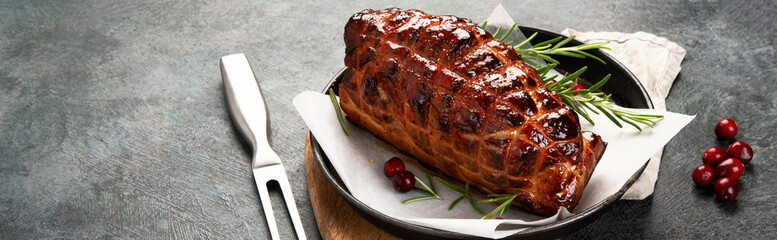 Baked ham with vegetables on dark background.