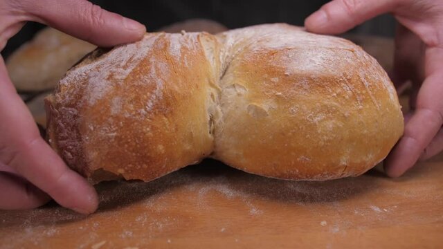 hands tearing loaf of bread slow motion