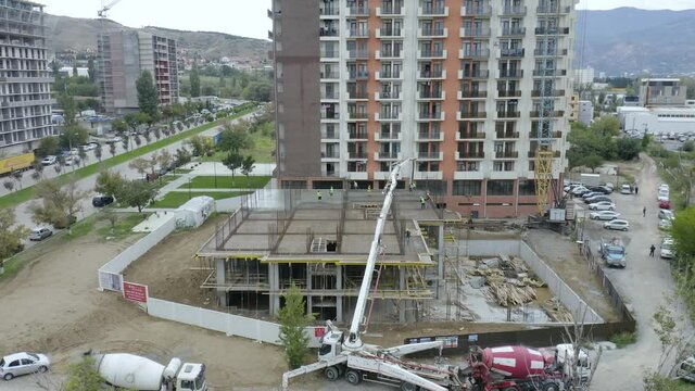 Mixer Trucks, Mobile Crane, And Manual Workers During Concrete Pouring Of Slab At Construction Site. aerial approach