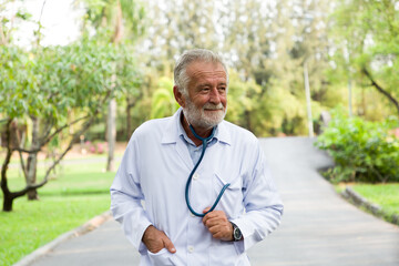 Smiling male doctor with stethoscope wear white uniform standing in the park