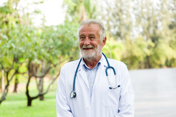 Smiling male doctor with stethoscope wear white uniform standing in the park