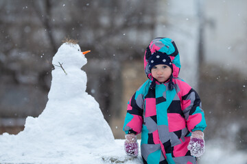 Fototapeta na wymiar Girl hugs a snowman, winter walk