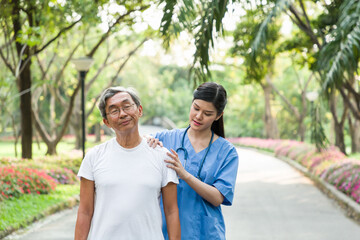 Asian young woman nurse taking care of an elderly man patient in the garden. Young happy doctor with older man outdoor with nature background.
