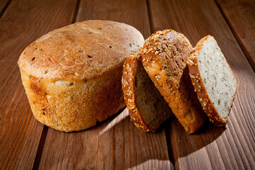 A loaf of delicious white bread made from natural products, on hops with flax saturation, without baker's yeast, on a wooden table surface.