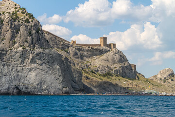 Fototapeta na wymiar Wall and towers of the Genoese fortress on a rock above the sea. View of the fortress in Sudak from the water.