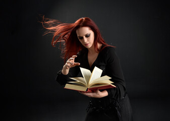 close up portrait of red haired woman wearing  black victorian witch costume.  standing pose, with ...