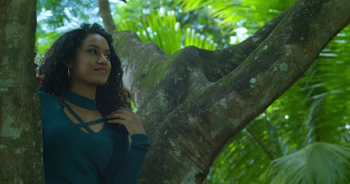 A young curly hair girl smile while sitting in a large tree trunk