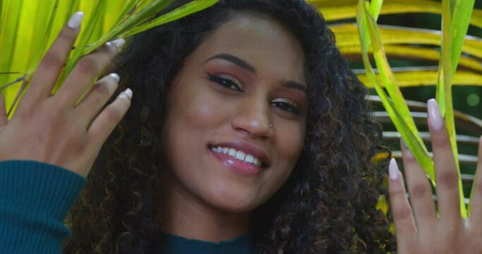A girl drops palm branches over her face while smiling