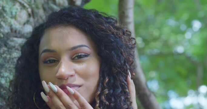 Close up of a curly hair girl blowing a kiss on a sunny day in the tropics
