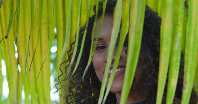 Young girl paths a palm branch revealing her pretty face