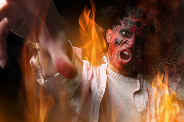 Scary zombie man on dark background with burning flame