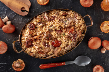 Risotto ai funghi, mushroom rice, with ingredients, overhead flat lay shot on a black background
