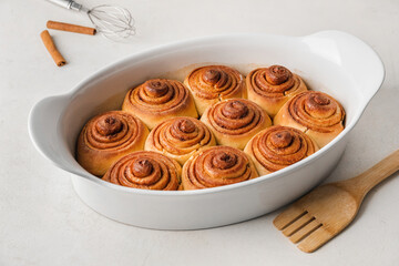 Baking dish with tasty cinnamon rolls on table