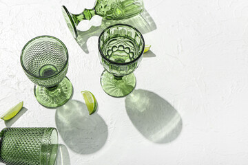 Beautiful glasses and lime on light background
