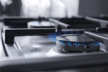 Gas burner with blue flame on domestic stove, closeup