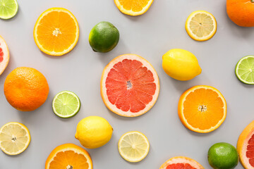 Fototapeta na wymiar Slices of different citrus fruits on grey background