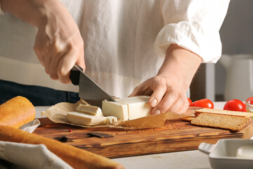 Woman cutting feta cheese on table in kitchen