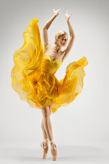 Dancing Woman in Yellow Dress. Ballerina in Shoes Dance Modern Art Ballet over Light Gray...