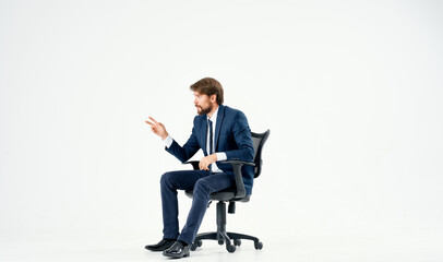 bearded man in a suit sitting in an office chair work light background
