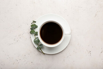 Obraz na płótnie Canvas Cup of coffee and fresh eucalyptus branch on light background