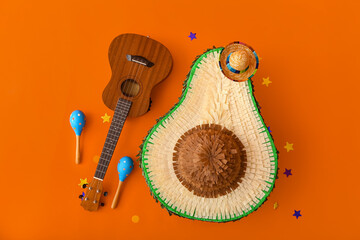 Mexican pinata with sombrero hat, maracas and guitar on orange background