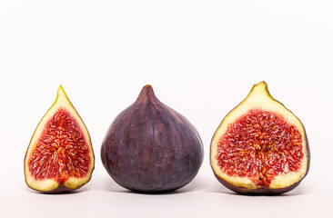 Ripe figs and half a fruit on a green leaf background. Fresh fruit. White background.