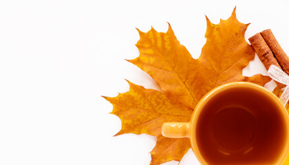 A ceramic cup of tea on a maple autumn leaf and a stick of cinnamon. Close-up. White background with a place to copy. The concept of seasonal warming drinks.