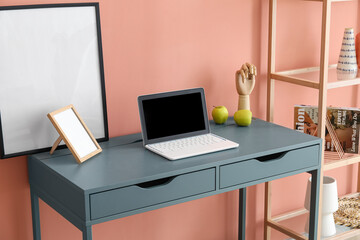 Laptop on modern table near color wall