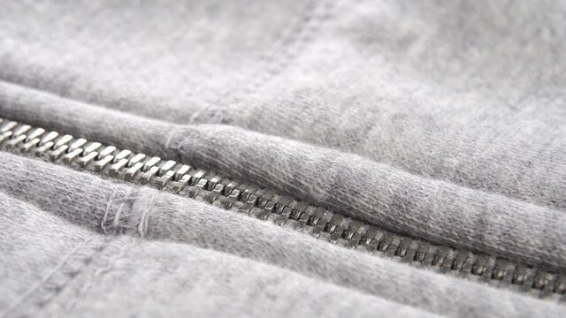 Zip up the gray hoodie. Close-up of a metal zipper. Macro