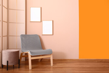 Cozy armchair and pouf near color wall with blank posters