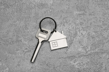 Key with stylish house shape keychain on grunge background
